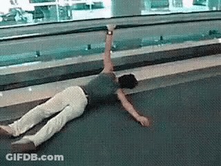 A Man Is Laying On The Floor With His Arms Outstretched . GIF