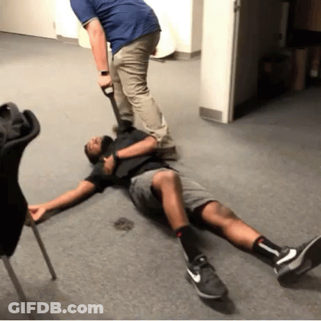 A Man Is Laying On The Floor With His Legs Crossed While Another Man Holds A Shovel . GIF