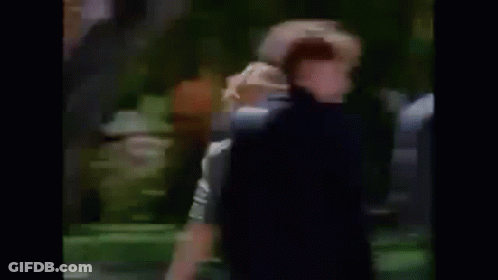 A Man Is Laying On The Grass In A Park . GIF