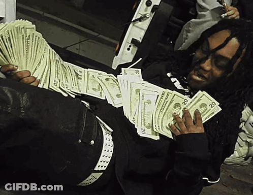 A Man Is Laying On The Ground Holding A Stack Of 20 Dollars GIF