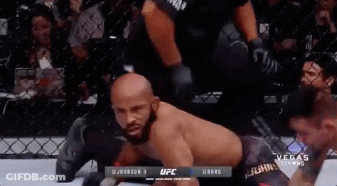 A Man Is Laying On The Ground In A Cage During A Boxing Match . GIF