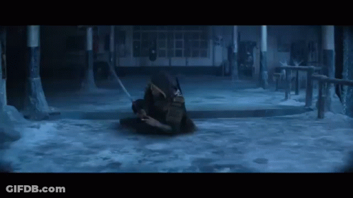 A Man Is Laying On The Ground In A Dark Room With A Sword In His Hand . GIF