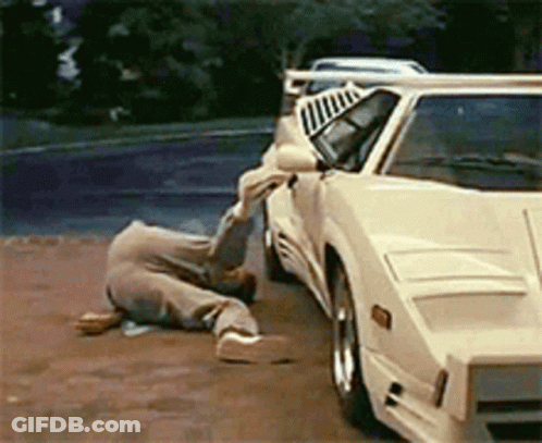 A Man Is Laying On The Ground In Front Of A White Car GIF