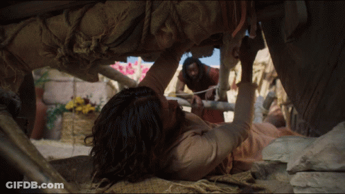 A Man Is Laying On The Ground While Another Man Stands Behind Him GIF