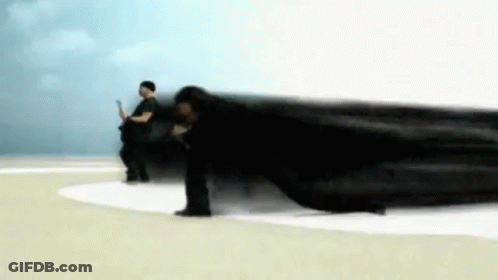 A Man Is Laying On The Ground While Another Man Stands In The Background . GIF