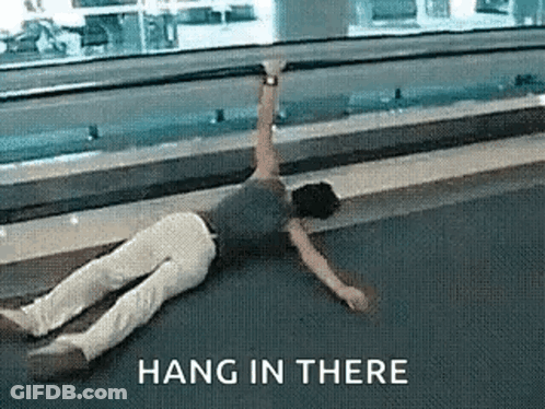 A Man Is Laying On The Ground With The Words Hang In There Above Him . GIF