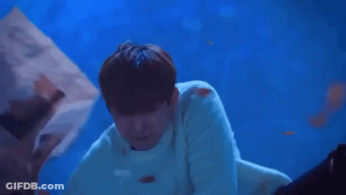 A Man Is Laying On Top Of A Woman In A Blue Water Tank . GIF