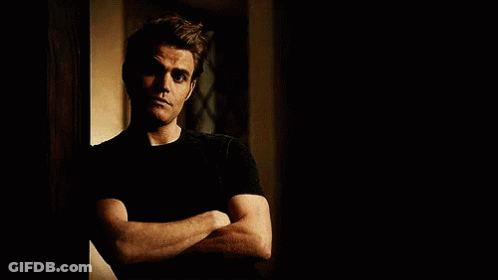 A Man Is Leaning Against A Wall With His Arms Crossed . GIF