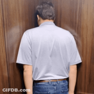 A Man Is Leaning Against A Wall With His Head Down GIF