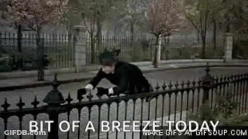 A Man Is Leaning Over A Fence With The Words Bit Of A Breeze Today Written Below Him GIF