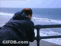 Man Leaning Over Railing Looking At Ocean GIF