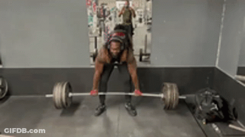 A Man Is Lifting A Barbell In A Gym In Front Of A Mirror GIF
