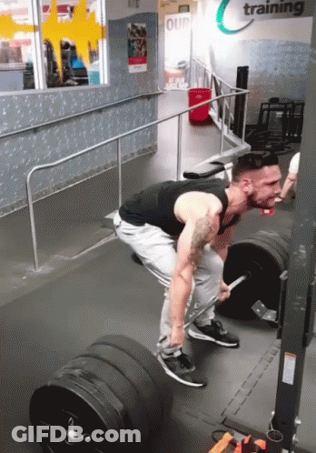 A Man Is Lifting A Barbell In A Gym That Says Training On The Wall GIF