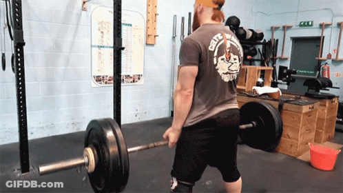 A Man Is Lifting A Barbell In A Gym Wearing A Shirt That Says City Of Death GIF