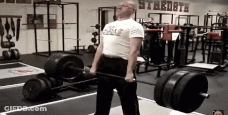 A Man Is Lifting A Barbell In A Gym With A Sign On The Wall That Says Strength . GIF