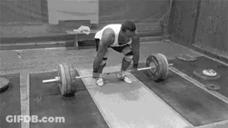 A Man Is Lifting A Barbell On A Platform In A Gym . GIF