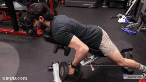 A Man Is Lifting A Dumbbell On A Bench In A Gym With Kapwing Written In The Corner GIF