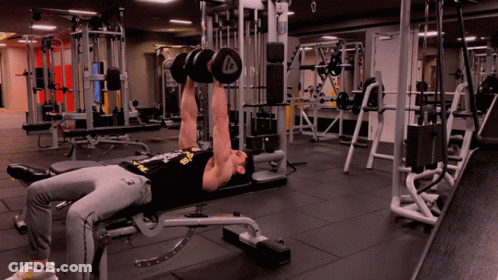 A Man Is Lifting Dumbbells In A Gym With The Letter A On The Dumbbell GIF