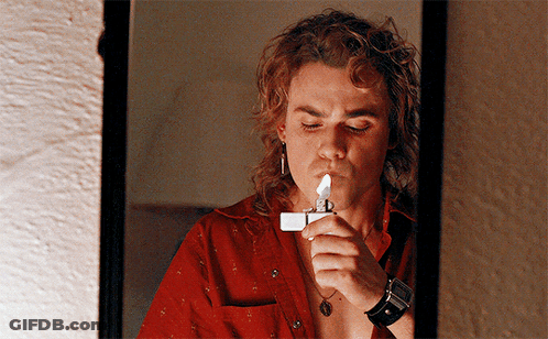 A Man Is Lighting A Lighter In Front Of A Mirror GIF