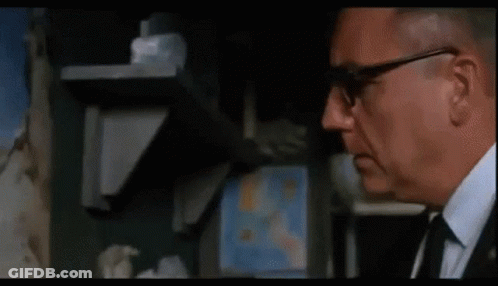 A Man Is Looking At A Painting On A Wall . GIF