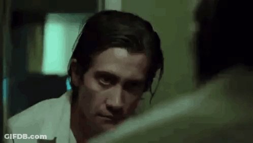 A Man Is Looking At Himself In The Mirror And Making A Funny Face . GIF
