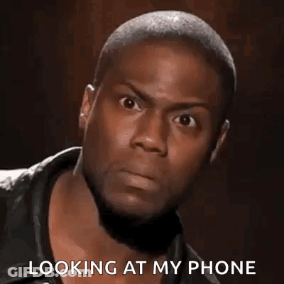 A Man Is Looking At His Phone While Wearing A Leather Jacket . GIF