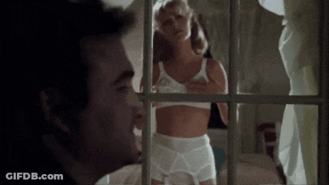 A Man Is Looking Out A Window At A Woman In Lingerie . GIF