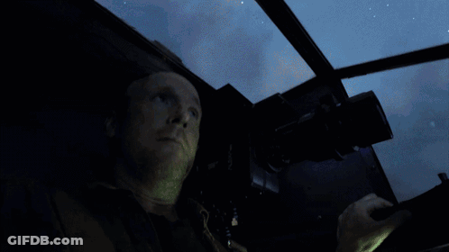 A Man Is Looking Out A Window With A Blue Light Behind Him GIF