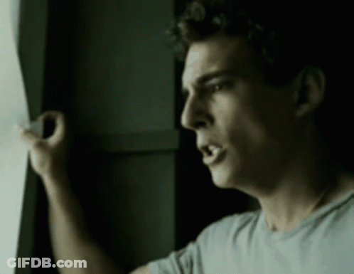 A Man Is Looking Out A Window With His Mouth Open GIF