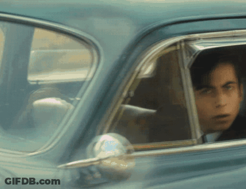 A Man Is Looking Out Of A Car Window GIF