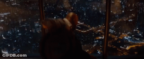 A Man Is Looking Out Of A Window At A City GIF