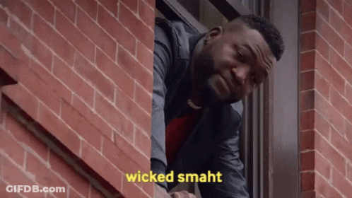 A Man Is Looking Out Of A Window With The Words Wicked Smaht Written On The Brick Wall Behind Him . GIF