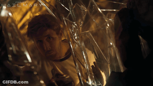 A Man Is Looking Through A Broken Glass Window With The Words Project Hailmary Behind Him GIF