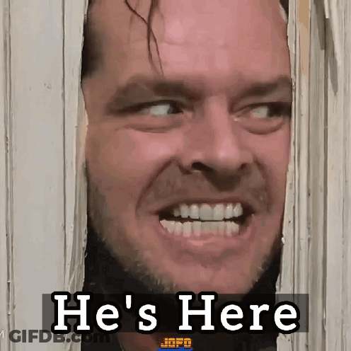 A Man Is Looking Through A Door With The Words He 'S Here Behind Him GIF