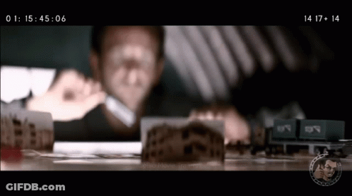 A Man Is Looking Through A Magnifying Glass At A Model Train Set GIF