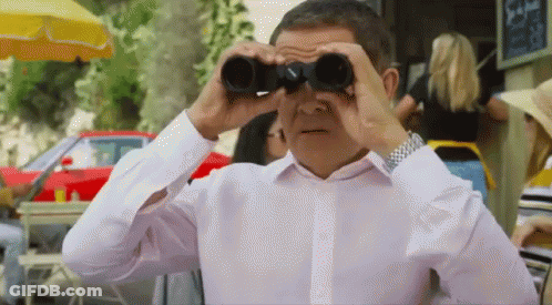 A Man Is Looking Through Binoculars In A Restaurant . GIF