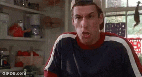 A Man Is Making A Funny Face In A Kitchen While Wearing A Baseball Cap . GIF