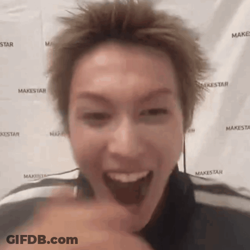 A Man Is Making A Funny Face In Front Of A Makestar Backdrop . GIF