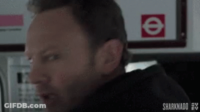 A Man Is Making A Funny Face In Front Of A Sign That Says E On It . GIF