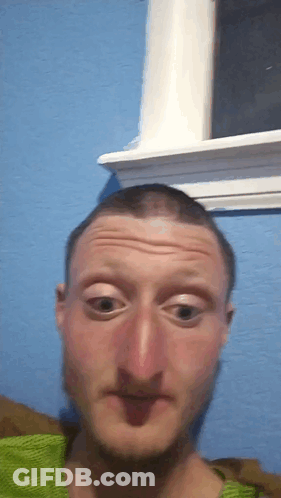 A Man Is Making A Funny Face In Front Of A Window GIF