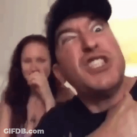 A Man Is Making A Funny Face While A Woman Laughs In The Background . GIF