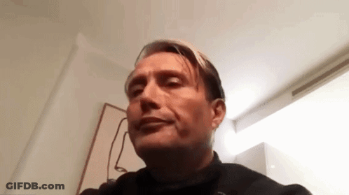 A Man Is Making A Funny Face While Sitting In A Chair In A Room . GIF