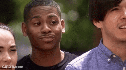 A Man Is Making A Funny Face While Standing Next To A Woman And Another Man . GIF