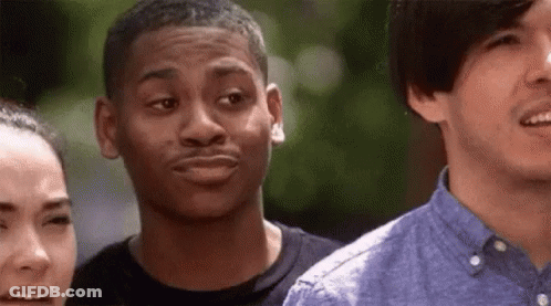 A Man Is Making A Funny Face While Standing Next To Two Other Men . GIF