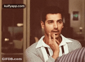 A Man Is Making A Funny Face While Talking To Another Man . GIF
