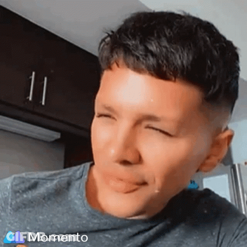 A Man Is Making A Funny Face With His Eyes Closed And A Momento Logo In The Corner GIF