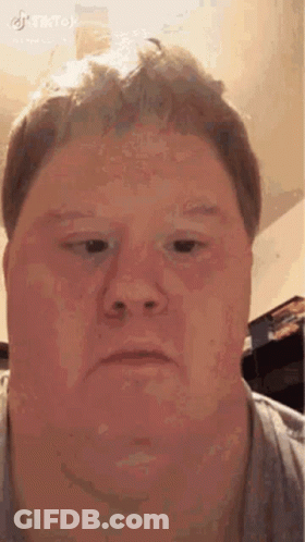 A Man Is Making A Funny Face With His Eyes Closed . GIF