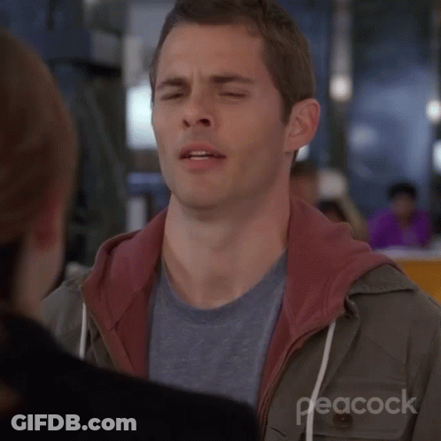 A Man Is Making A Funny Face With His Eyes Closed While Talking To A Woman . GIF