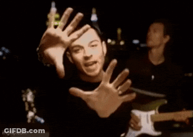 A Man Is Making A Funny Face With His Hands While Playing A Guitar In A Band . GIF
