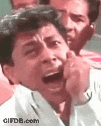 A Man Is Making A Funny Face With His Mouth Open In A Crowd . GIF